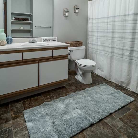 Thumbnail 13 of 13 A bathroom with a toilet, sink, and shower.