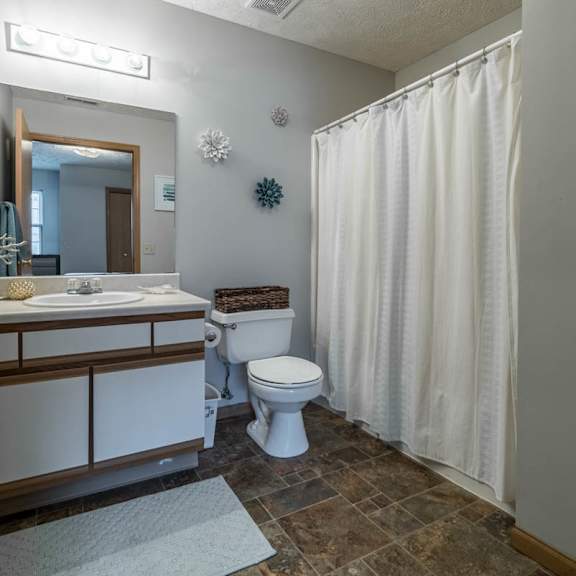Thumbnail 11 of 13 A bathroom with a toilet, sink, and shower curtain.