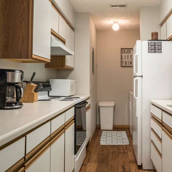 Thumbnail 6 of 13 A kitchen with white appliances and white and oak cabinets.
