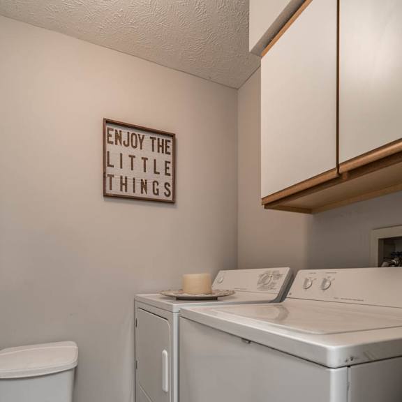Thumbnail 7 of 13 A laundry room with a washer and dryer and cabinet above them