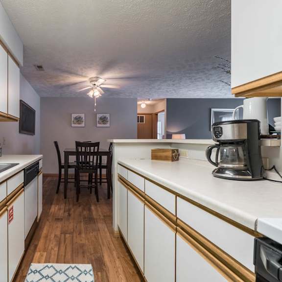 Thumbnail 8 of 13 A kitchen with white cabinets and a wooden floor.