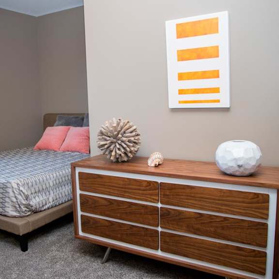 Thumbnail 10 of 14 A bedroom with a bed, dresser, and a picture on the wall.
