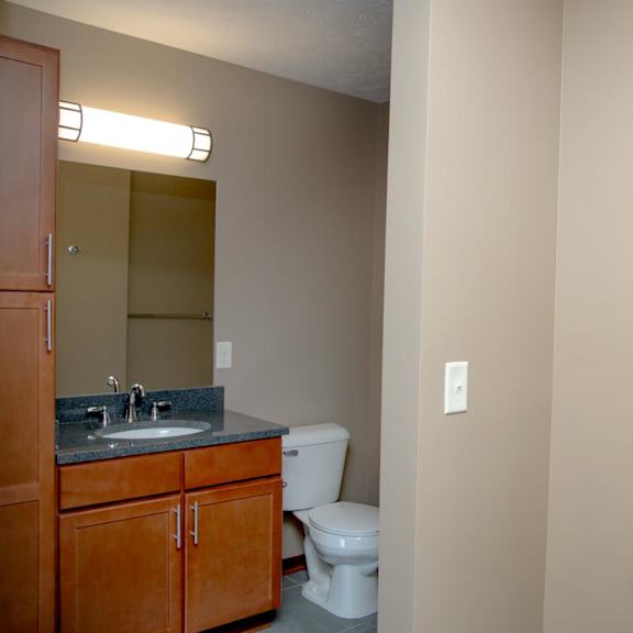 Thumbnail 9 of 15 A bathroom with a toilet, sink, and shelving.