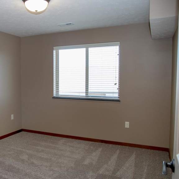 Thumbnail 12 of 15 A room with a carpeted floor and a window with blinds.