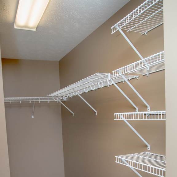 Thumbnail 11 of 15 Empty shelves in a walk in closet with a carpeted floor.