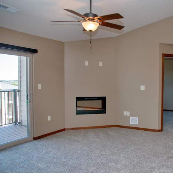 Thumbnail 5 of 15 A living room with a fireplace and a ceiling fan.