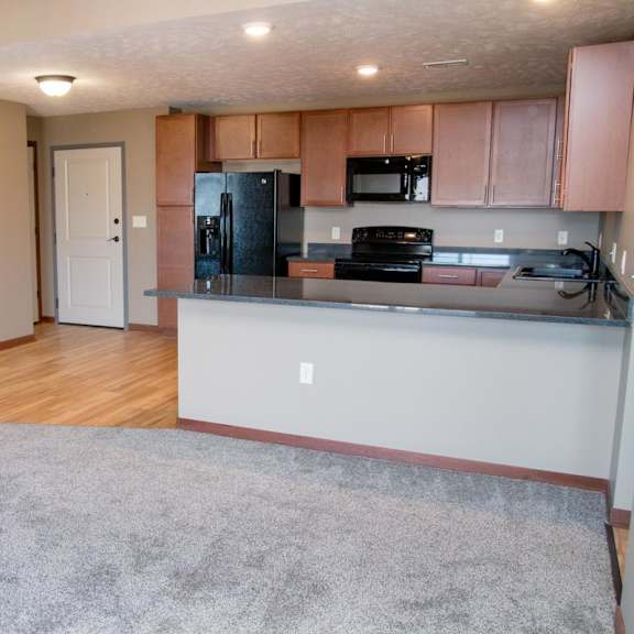 Thumbnail 6 of 15 A kitchen with a refrigerator, microwave, and stove, plus a peninsula for seating