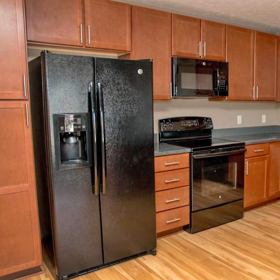 Thumbnail 3 of 15 U shaped kitchen with black appliances and warm brown cabinets