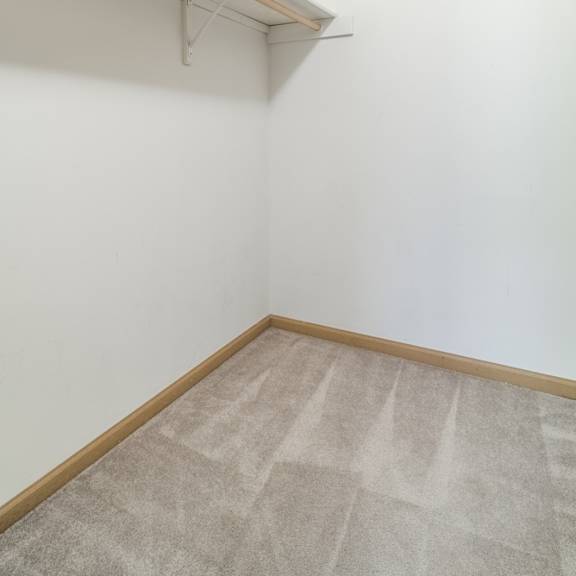 Thumbnail 9 of 11 A room with a carpeted floor and a white wall.