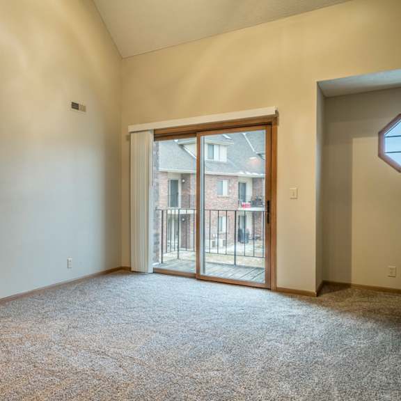 Thumbnail 2 of 16 Apartment living room with a carpeted floor and a sliding glass door leading to a balcony.