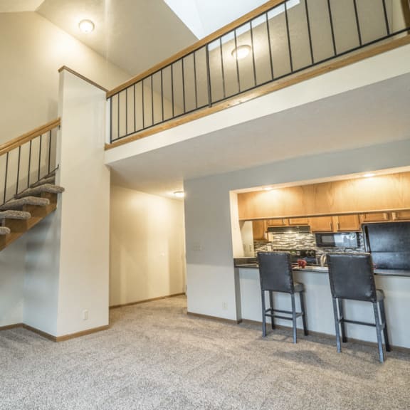 Thumbnail 11 of 15 a staircase leading to the loft area of an apartment above a kitchen and a bar