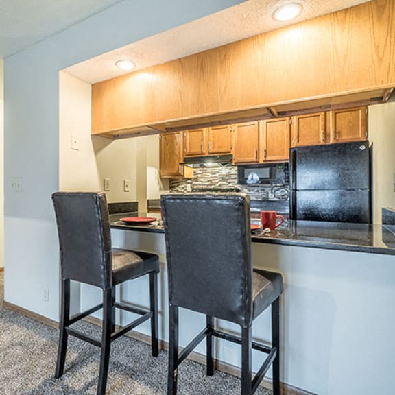 Thumbnail 4 of 15 Renovated kitchen with dark counter tops and seating at the counter at Fountain Glen Apartments