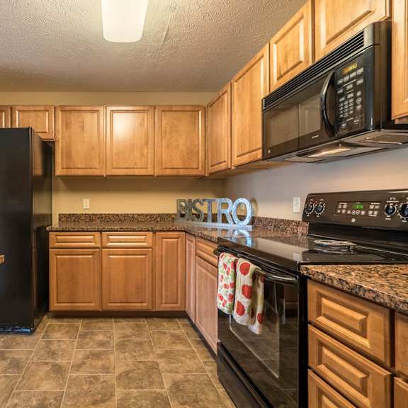 Thumbnail 6 of 12 a kitchen with black appliances and wooden cabinets