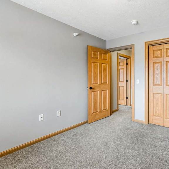 Thumbnail 25 of 31 Unfurnished bedroom featuring neutral carpet and wood-trim closet doors.
