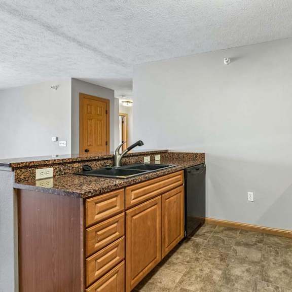 Thumbnail 20 of 31 Kitchen featuring granite peninsula counter, wood cabinets, and black appliances.