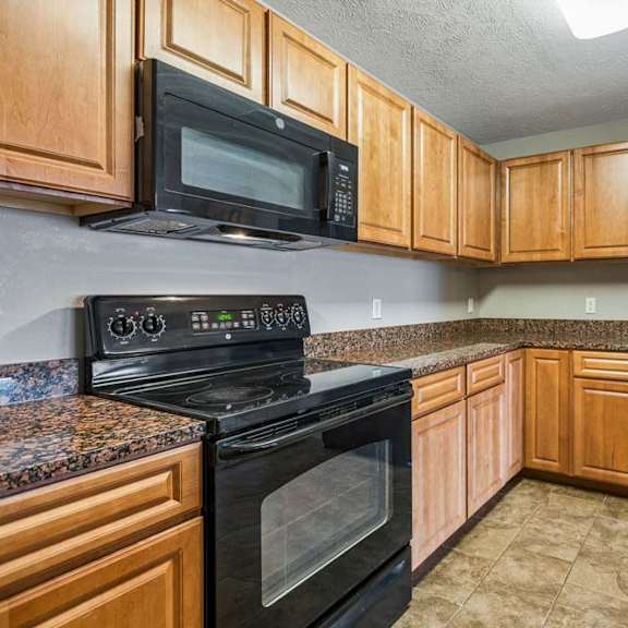 Thumbnail 19 of 31 Updated kitchen with wood cabinetry, granite countertops, and black appliances.