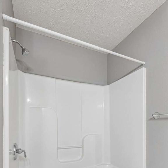 Thumbnail 23 of 26 Apartment bathroom with a white tub and shower combination, built-in surround, and a shower curtain rod, featuring a clean, neutral design.