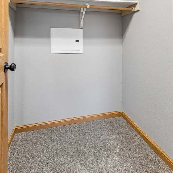 Thumbnail 21 of 26 Walk-in apartment closet with carpet flooring, built-in wire shelving, and hanging rods, providing organized storage space for clothing and accessories.