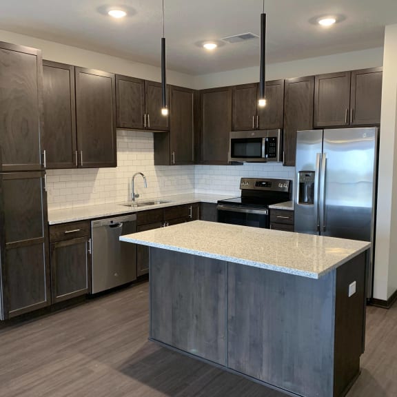 Thumbnail 3 of 16 Large kitchen with dark brown cabinets, including island with room for seating