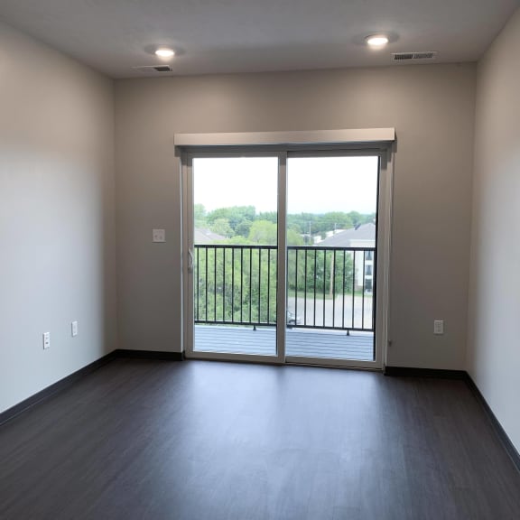 Thumbnail 6 of 16 Wood floored living room with glass sliding door that opens onto balcony
