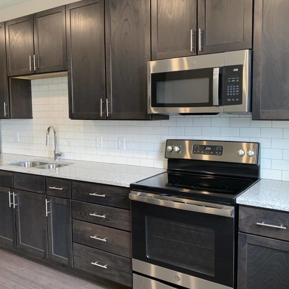 Thumbnail 2 of 18 Kitchen with dark brown cabinets and matching stainless steel appliances in Peace floorplan at Haven at Uptown