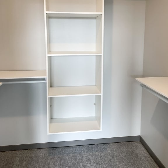 Thumbnail 13 of 17 All white shelving and rods in walk in closet in serenity floor plan at Haven at Uptown
