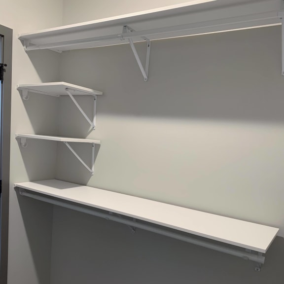 Thumbnail 15 of 17 All white shelving and rods in walk in closet in serenity floor plan at Haven at Uptown