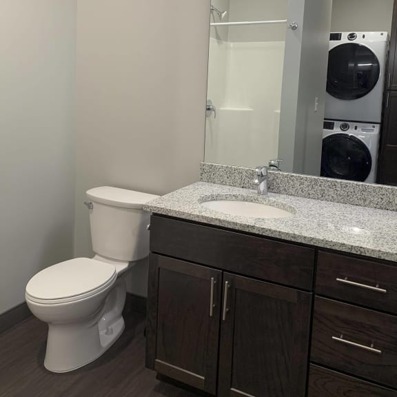Thumbnail 10 of 12 Bathroom with dark brown vanity with storage and large mirror at Haven at Uptown