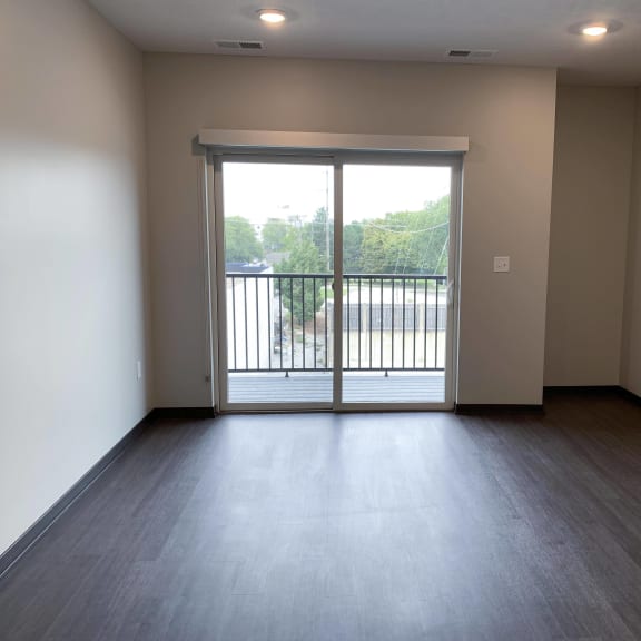 Thumbnail 7 of 15 Empty living area with wood floors and sliding door leading to patio