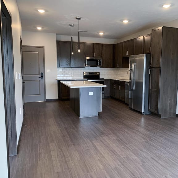 Thumbnail 3 of 15 Living area looking into connected kitchen with island at Haven at Uptown
