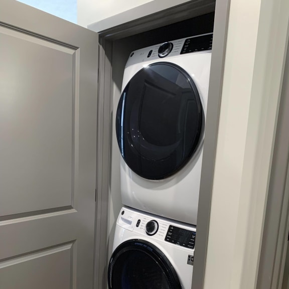 Thumbnail 6 of 11 Stacked front loader washer and dryer in a closet with door.