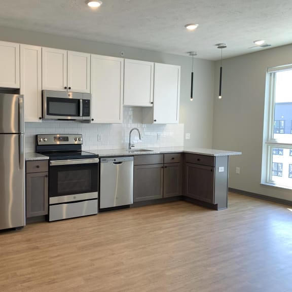 Thumbnail 2 of 11 Kitchen with brown lower cabinets, white upper cabinets and bar seating at Haven at Uptown.