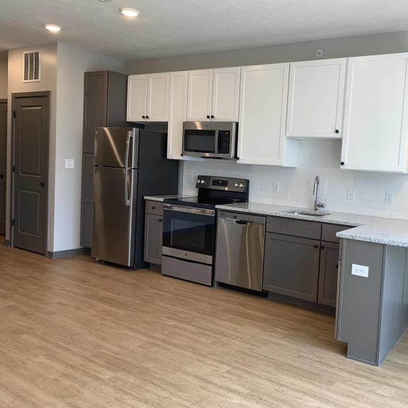 Thumbnail 4 of 11 Kitchen with brown lower cabinets, white upper cabinets and bar seating at Haven at Uptown
