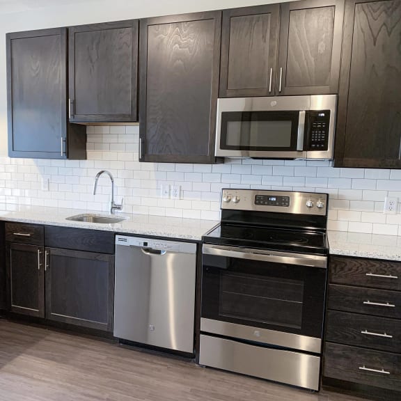 Thumbnail 14 of 23 Kitchen with warm brown upper and lower cabinets, white subway tile, and stainless steel appliances