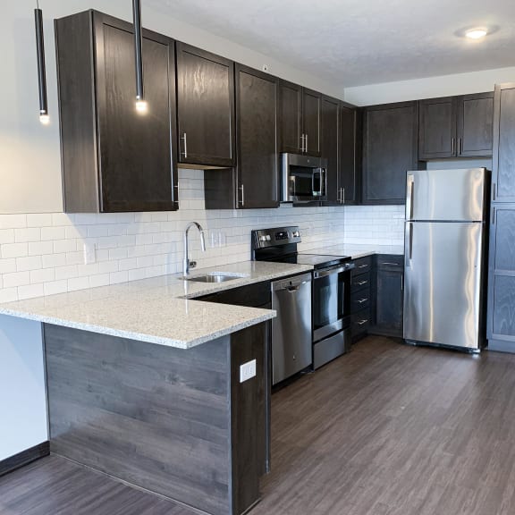 Thumbnail 12 of 23 Open kitchen with mocha finish and stainless steel matching appliances in the nest floorplan at haven at uptown in lincoln nebraska