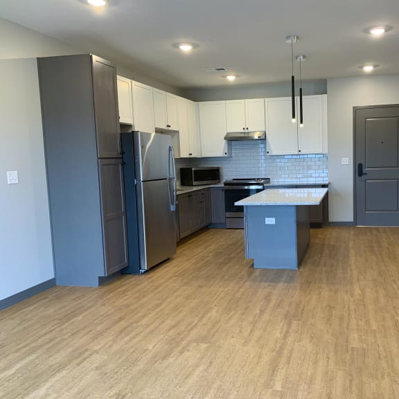 Thumbnail 2 of 13 Open kitchen to dining room with large granite countertop island at Haven at Uptown in Lincoln, Nebraska