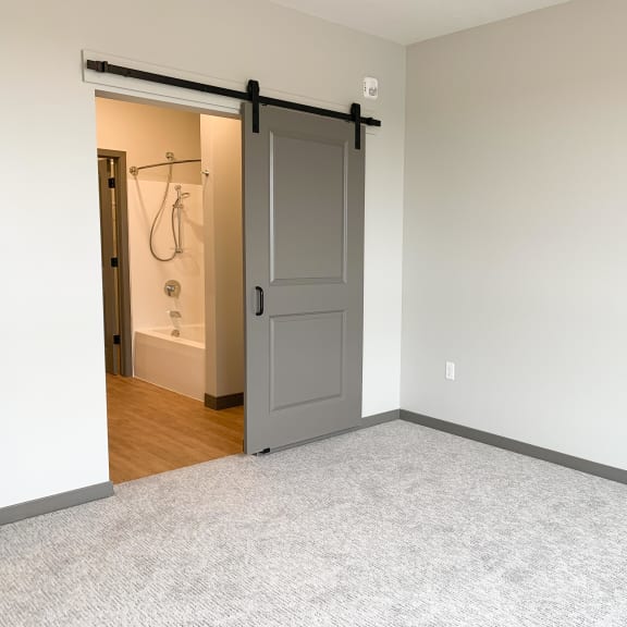 Thumbnail 10 of 13 Sliding barn door leading to bathroom in master bedroom at Haven at Uptown in Lincoln, Nebraska