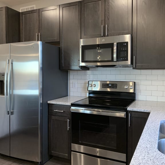 Thumbnail 3 of 18 Kitchen with dark brown cabinets and large kitchen island and matching stainless steel  appliances