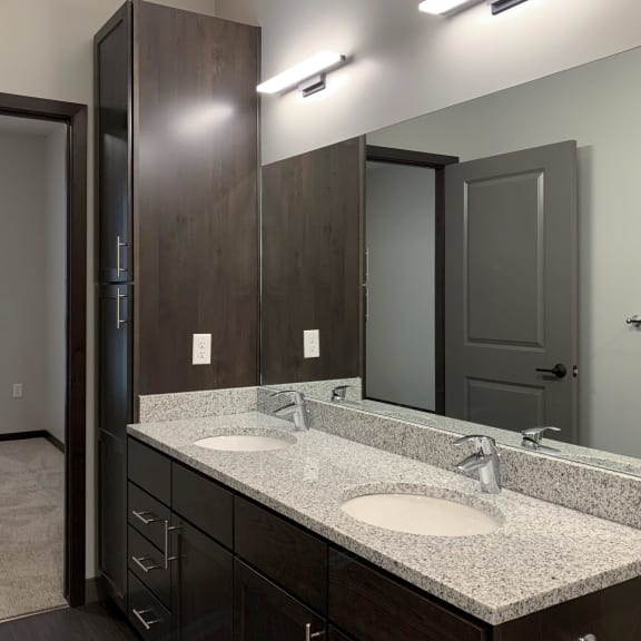 Thumbnail 16 of 18 bathroom with dual sinks and dark brown cabinets and storage closet
