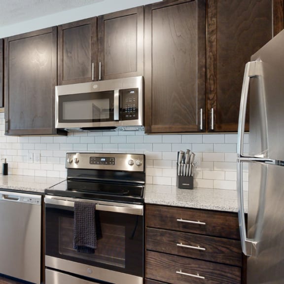 Thumbnail 3 of 23 a kitchen with dark wood cabinets and stainless steel appliances