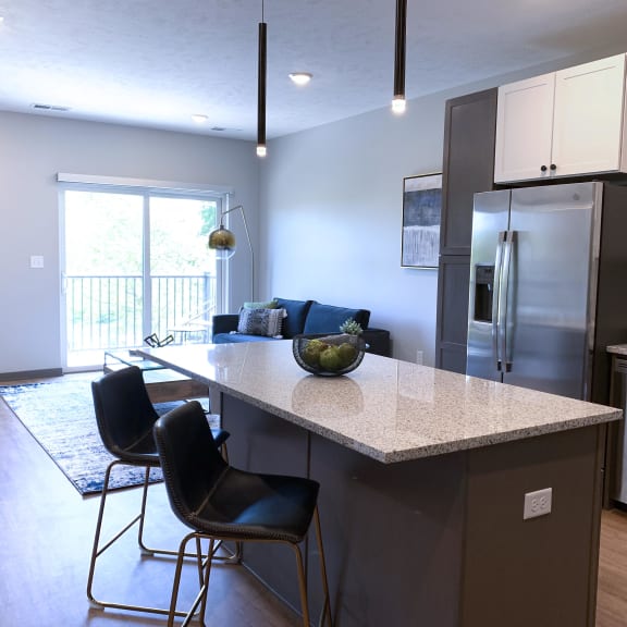 Thumbnail 3 of 19 Furnished kitchen in the Slate finish with two tone cabinets, hard wood style flooring, and granite counter tops in the Bliss floor plan at Haven at Uptown