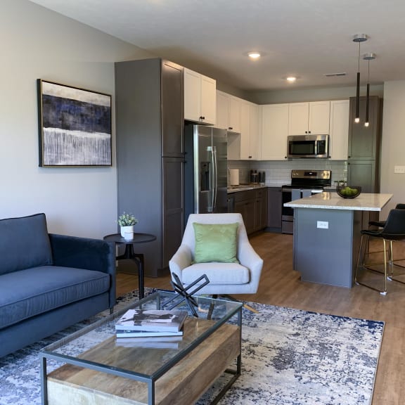 Thumbnail 9 of 19 Furnished open concept living room looking into large kitchen in Bliss floor plan at Haven at Uptown in Lincoln.