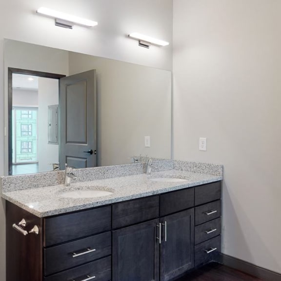 Thumbnail 7 of 17 Dual sinks and light granite counter tops, as well is dark wood cabinetry for extra storage in the bathroom at Haven at Uptown in Linooln, NE