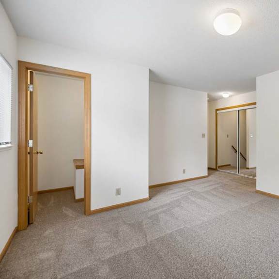 Thumbnail 34 of 37 Carpeted bedroom with mirrored closet doors, a side window, and an open doorway leading to an adjacent interior space.