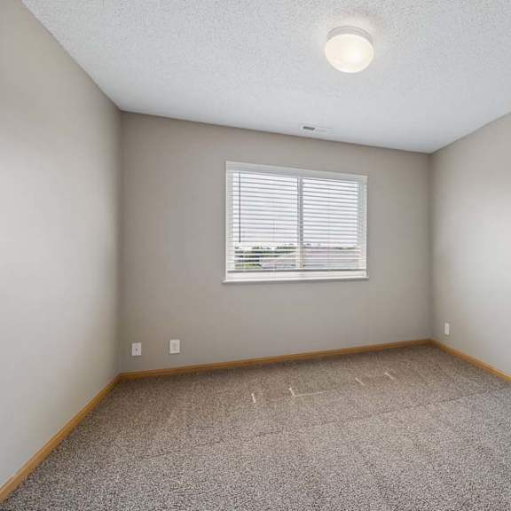 Thumbnail 16 of 21 Sunlit bedroom with wall-to-wall carpeting and a window with blinds, offering open space for flexible furniture placement.