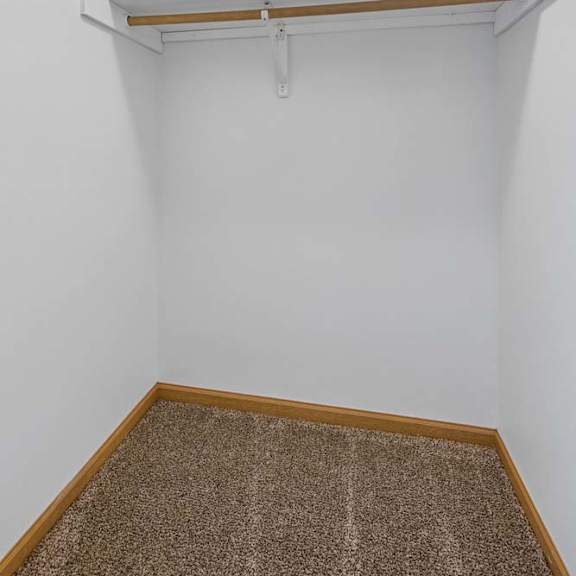 Thumbnail 18 of 21 Carpeted closet with a wide overhead shelf and hanging rod, providing dedicated storage within the apartment.