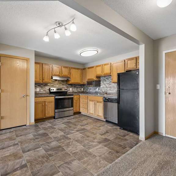 Thumbnail 11 of 21 Apartment entry opens to an updated kitchen with oak cabinetry, mosaic backsplash, patterned flooring, and full-size appliances.