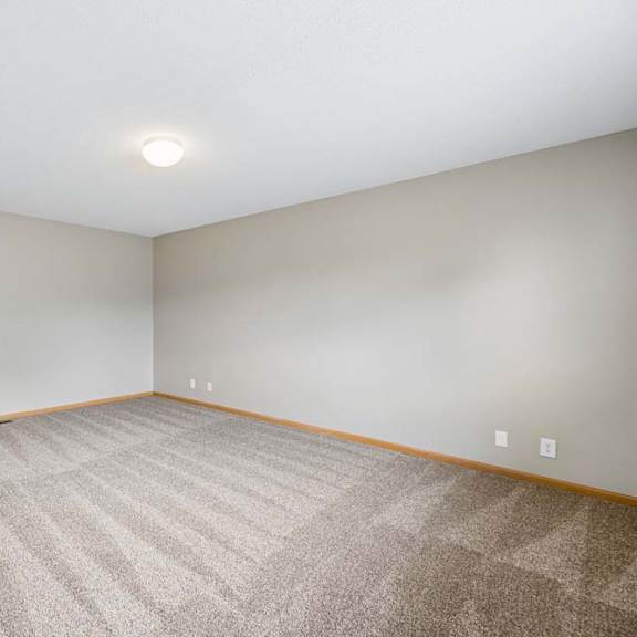Thumbnail 13 of 18 Spacious apartment bedroom with carpeted flooring, neutral walls, and a large window providing natural light.