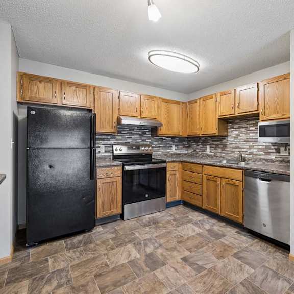 Thumbnail 4 of 18 Apartment kitchen with wood cabinetry, black appliances, a tile backsplash, laminate countertops, a pantry with built-in shelving, and a functional U-shaped layout.