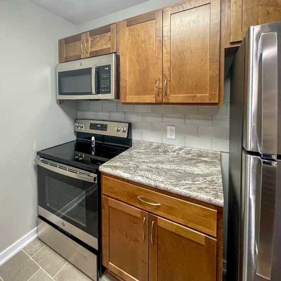 Thumbnail 9 of 12 a kitchen with updated wooden cabinets, granite countertops, and stainless steel appliances
